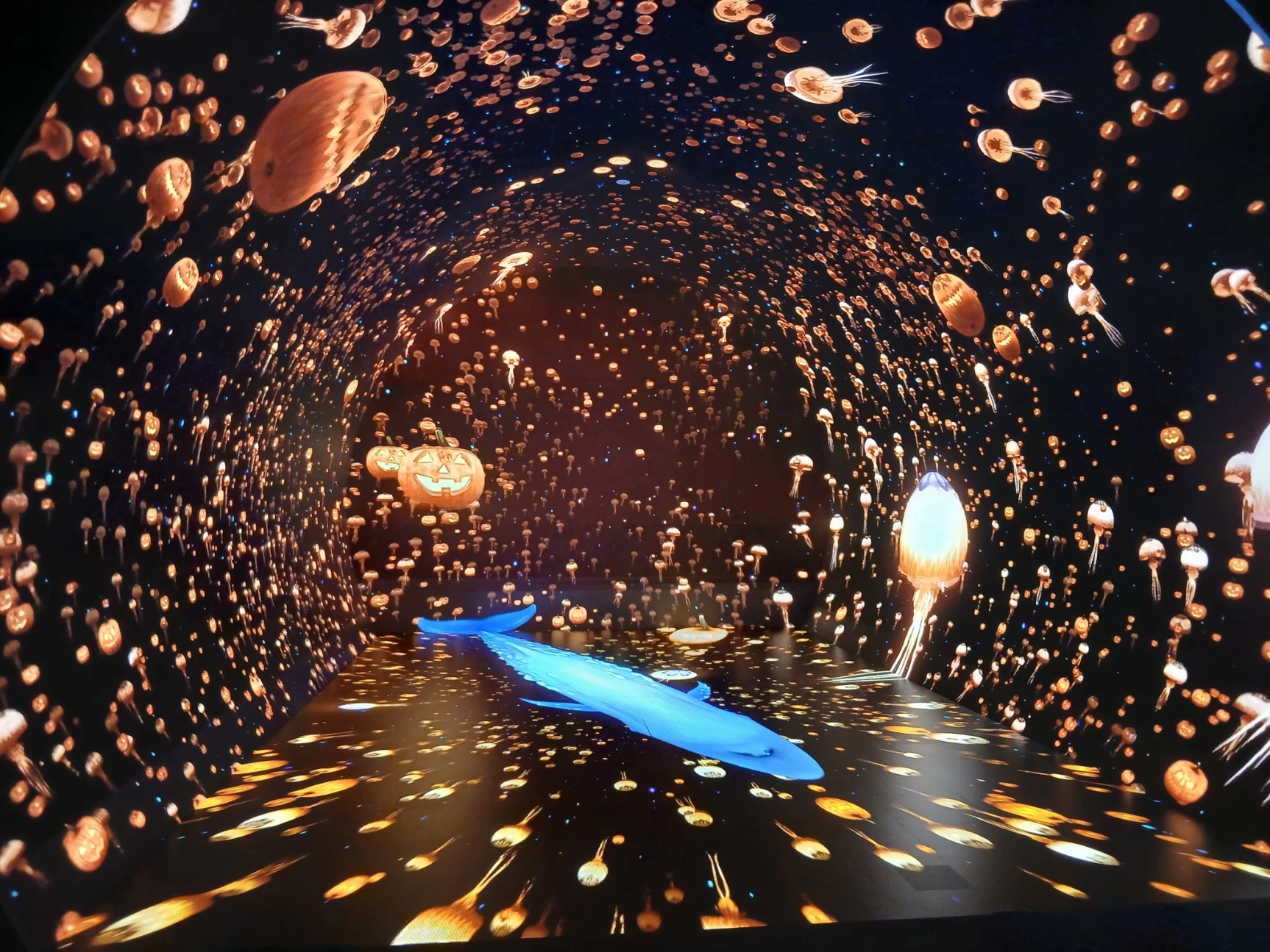 一面のカボチャとクラゲがオレンジ色に染まるLEDトンネルを、青いクジラがゆったりと横切る。
