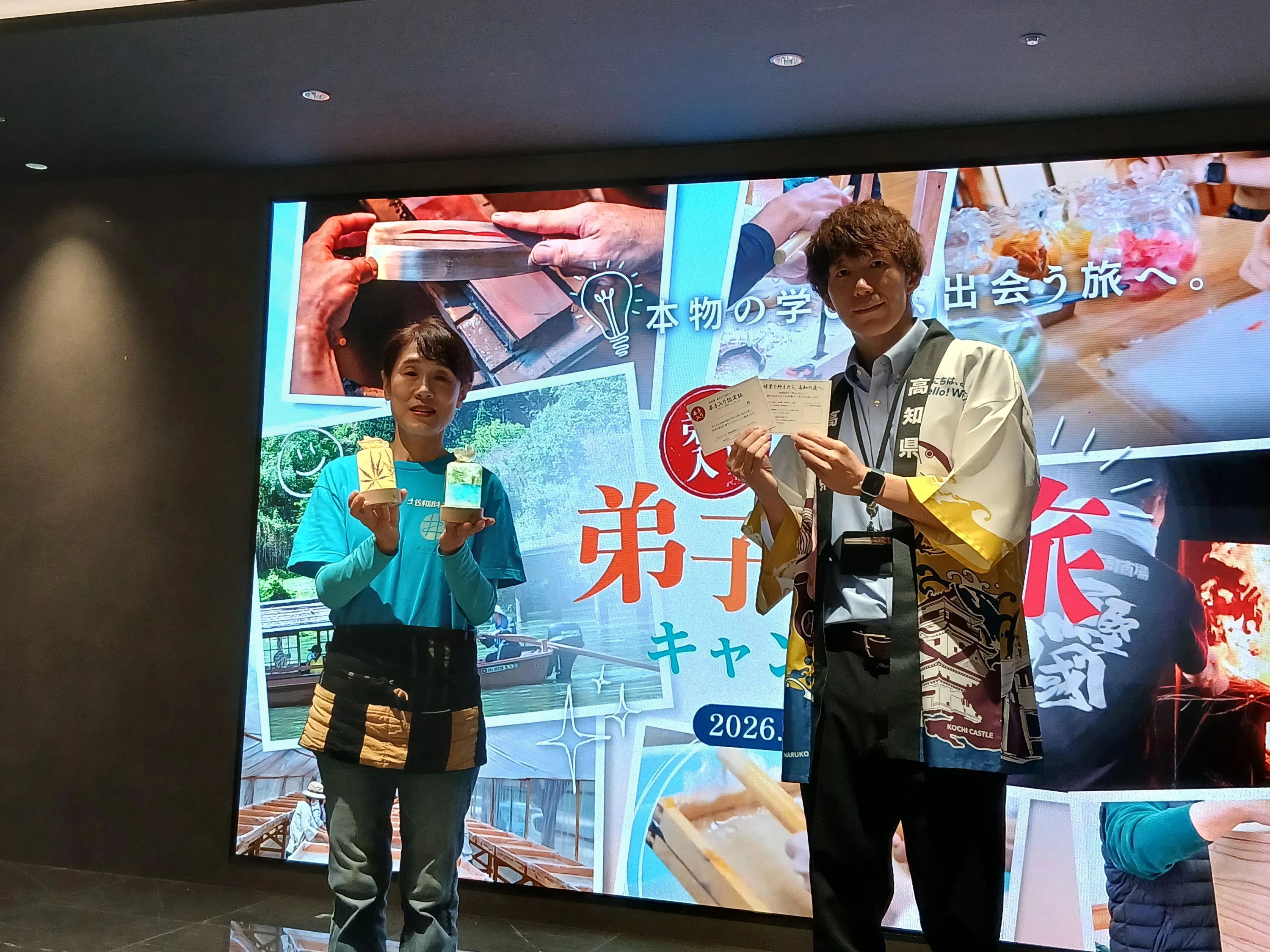 フォトセッションで、和紙ランプシェードと弟子入り認定証を紹介する井上さん(左)と西村さん(右)