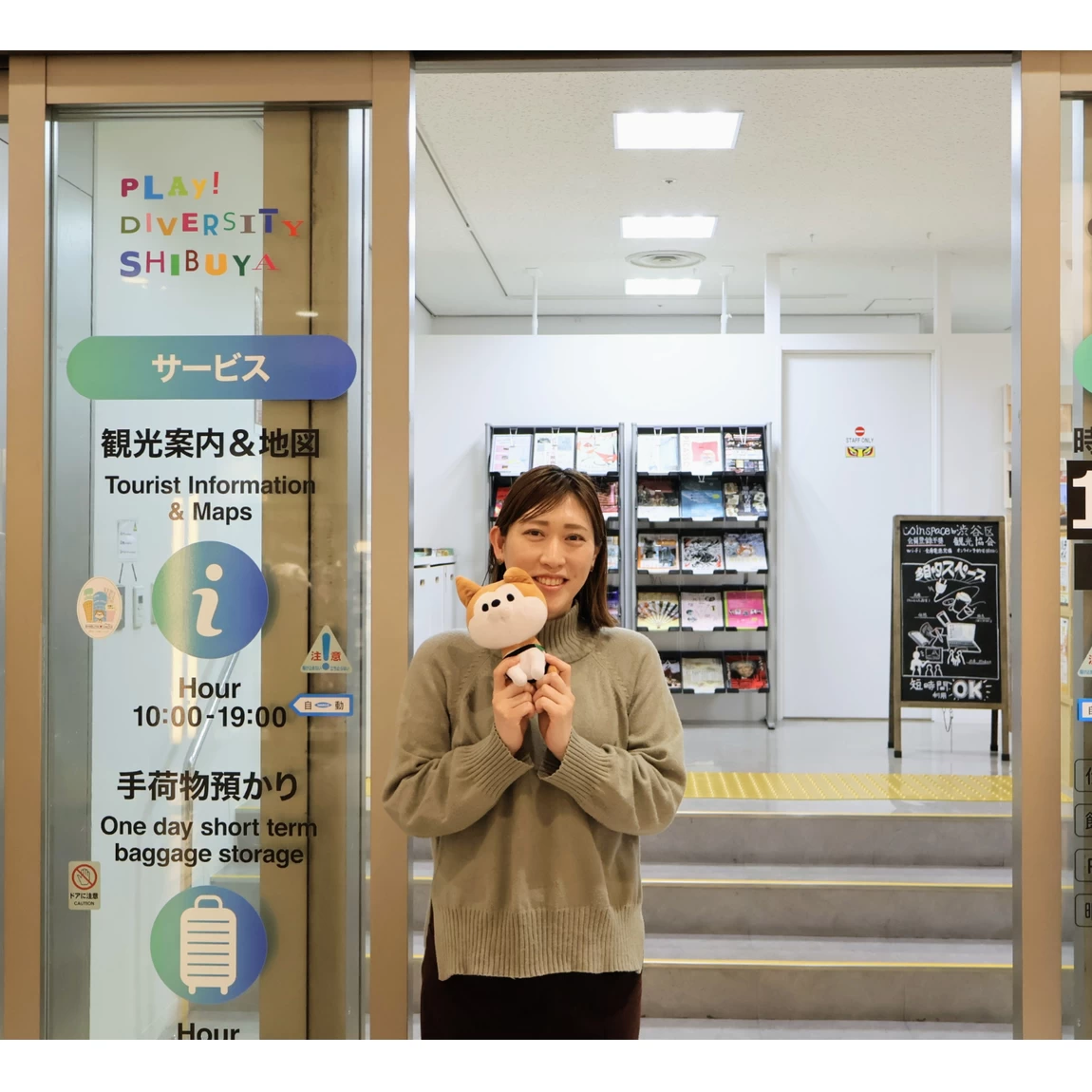 渋谷区観光協会の公式キャラクター「SHIBUYA♡HACHI」（シブヤラブハチ）のぬいぐるみを持った西さん