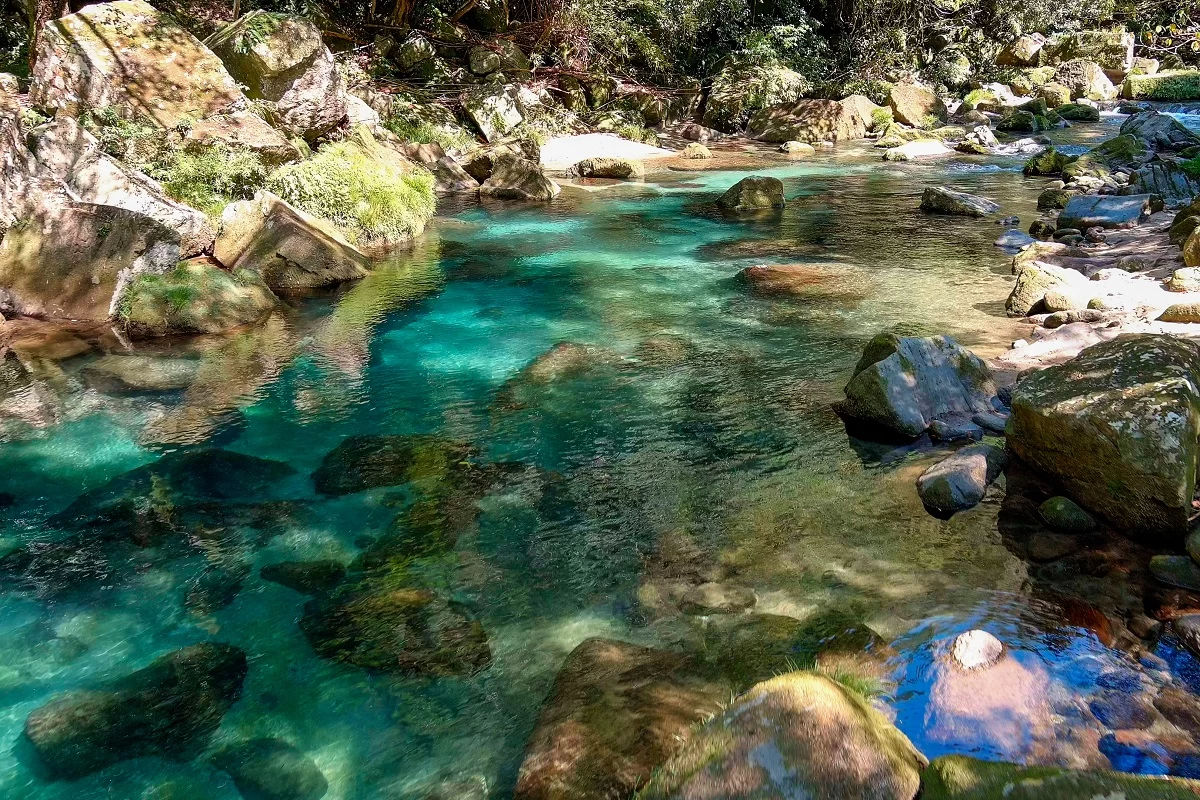 滝から流れるエメラルドグリーンの水
