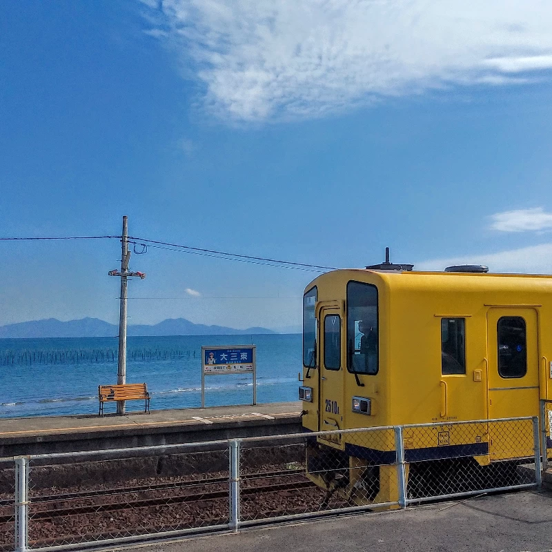 目の前の青い海に、黄色い列車が映える