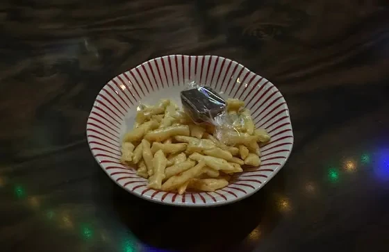 お通しで提供されている「こざかなくん」というピリ辛のスナックとチョコレート